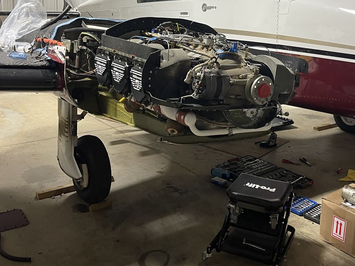 An aircraft engine with the cowling removed, mid-maintenance in the hangar
